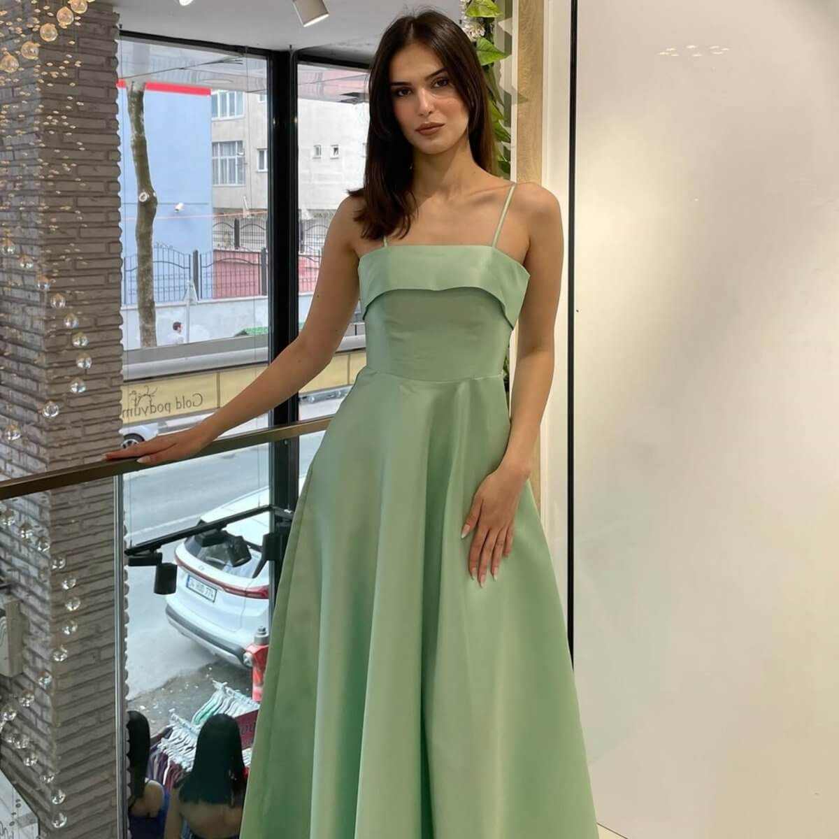 Woman wearing elegant solid color sleeveless backless tube top maxi summer dress in light green.