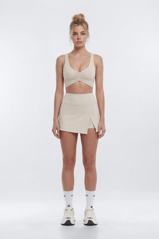 Woman wearing a beige sleeveless top and skirt set on a white background