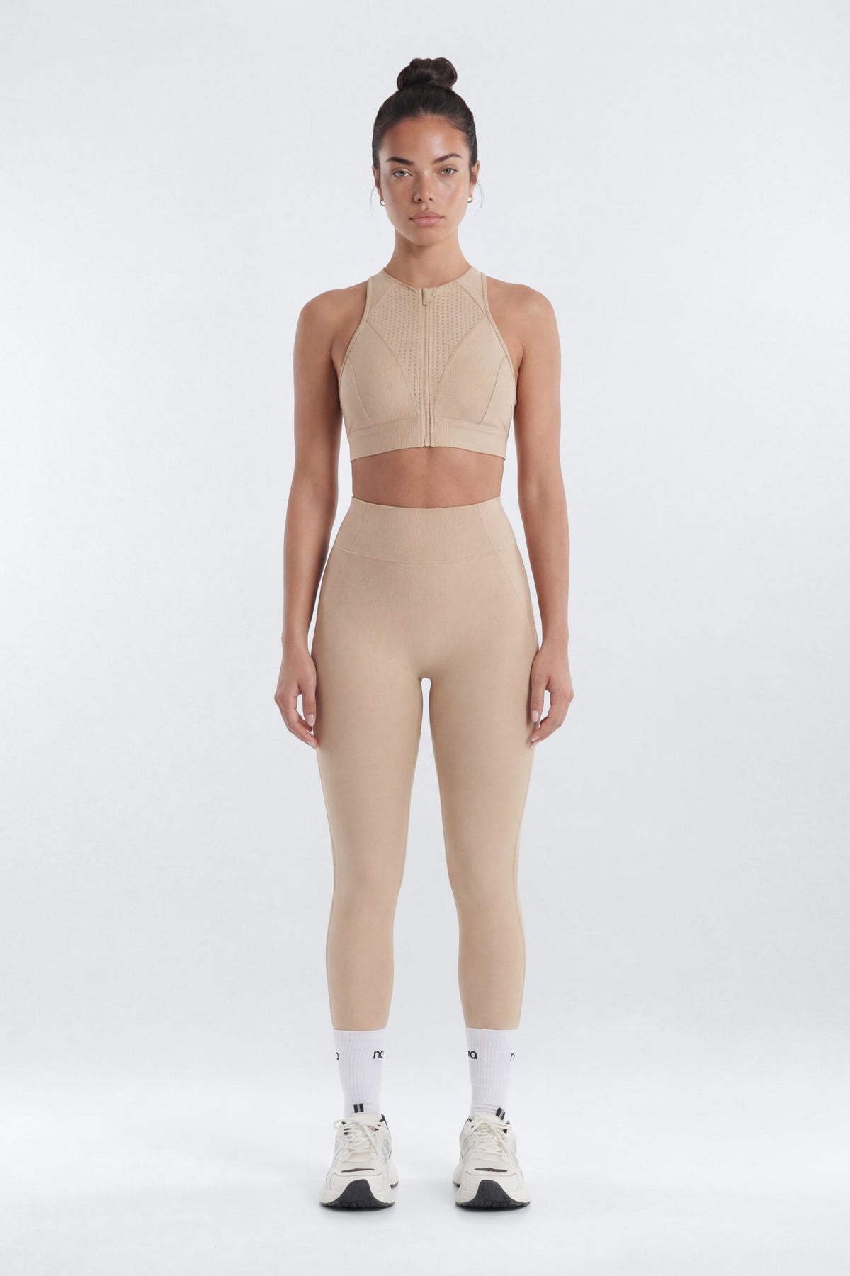 Woman wearing a beige athletic outfit on a white background