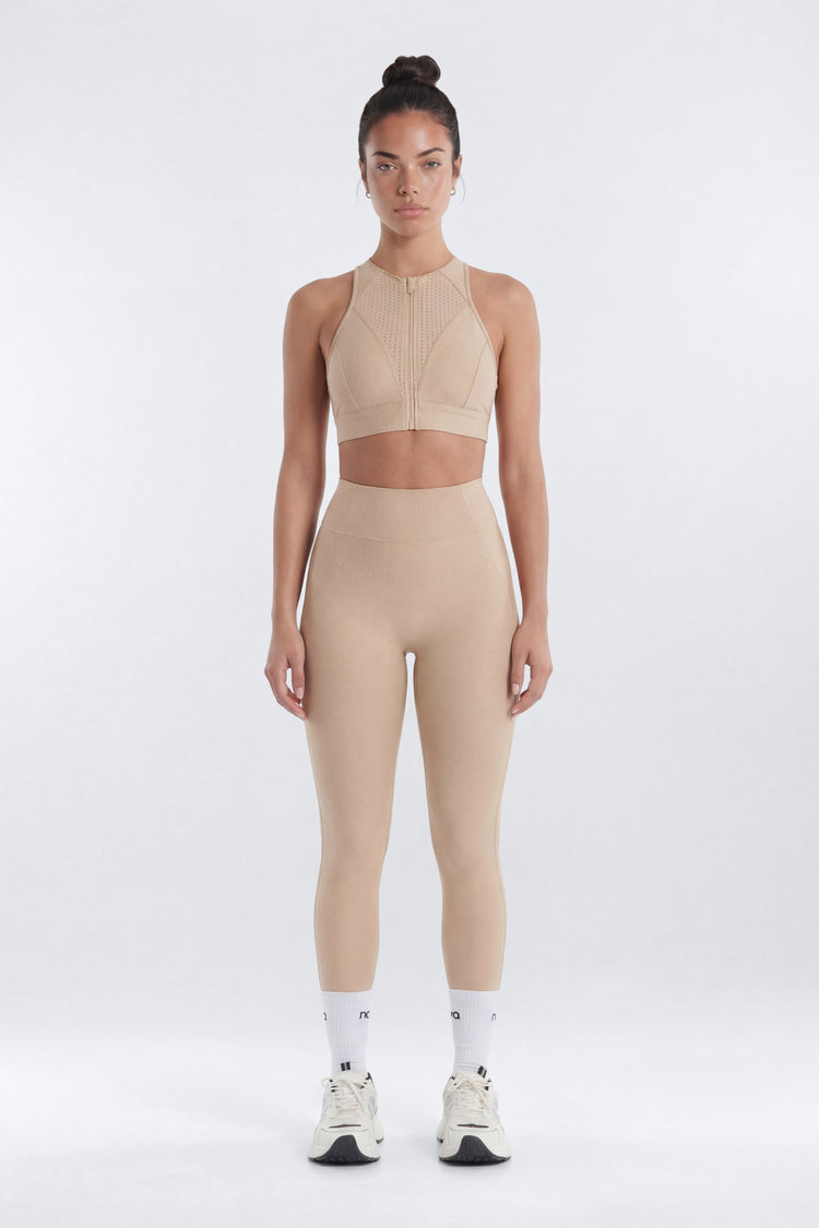Woman wearing a beige athletic outfit on a white background