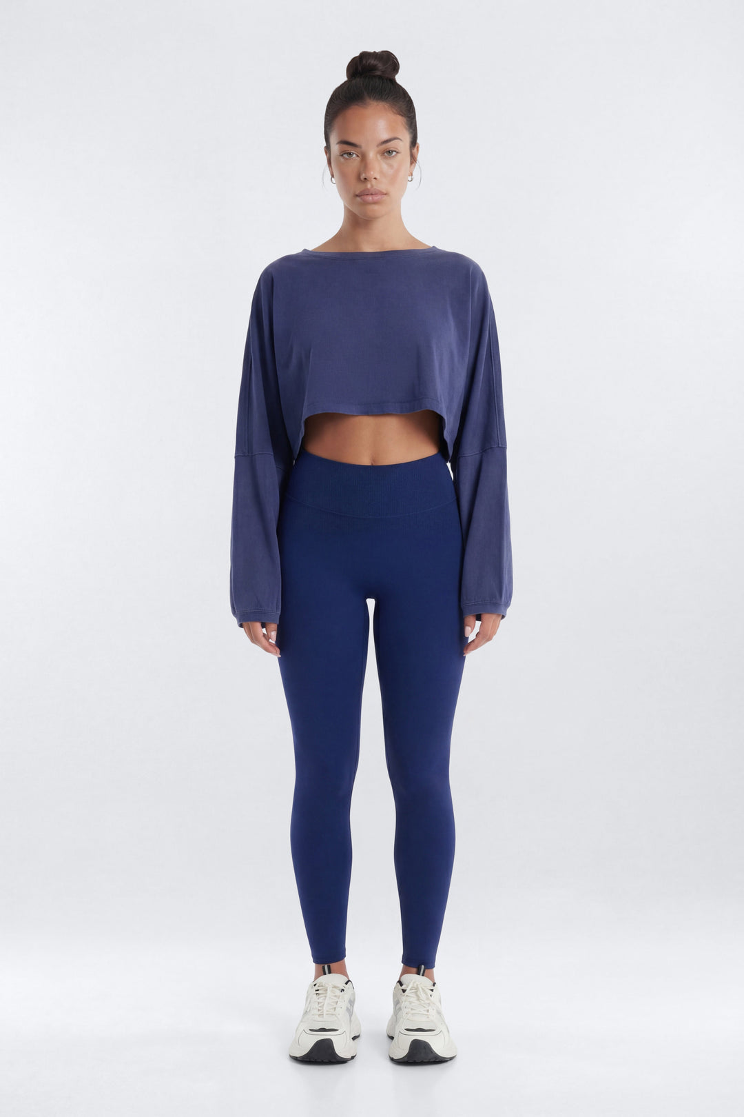 Person wearing a blue long-sleeve crop top and leggings on a white background