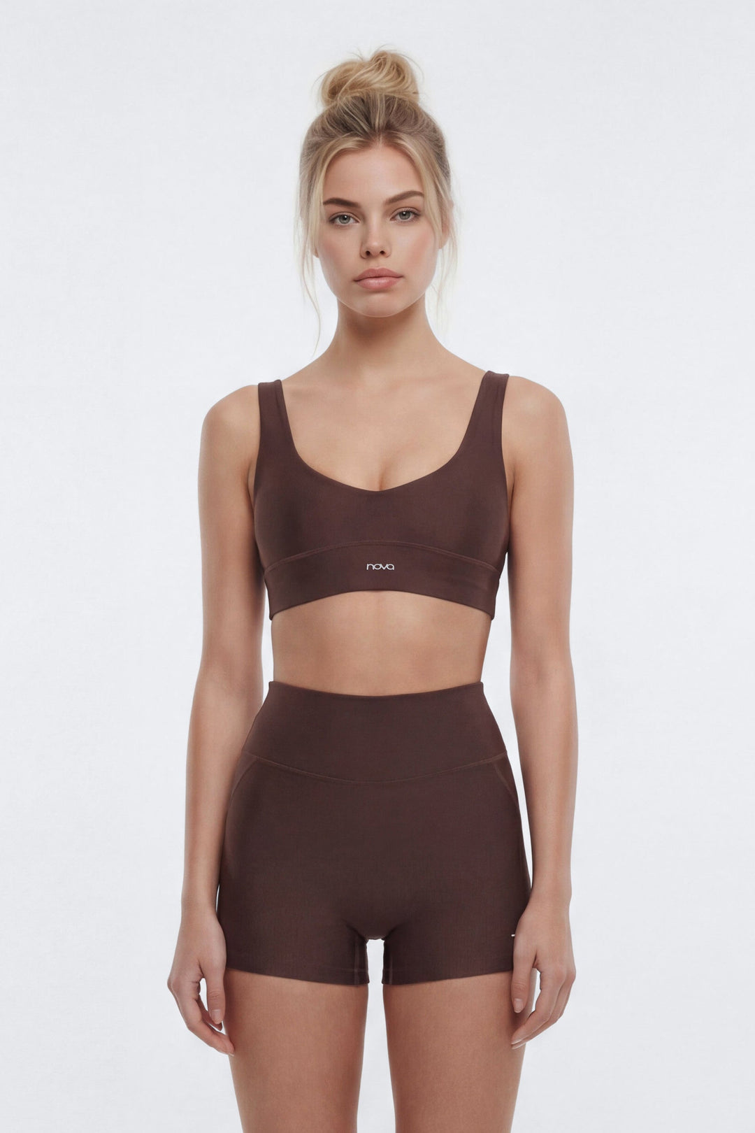 Woman wearing a brown sports bra and shorts set on a white background