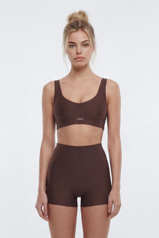 Woman wearing a brown sports bra and shorts set on a white background