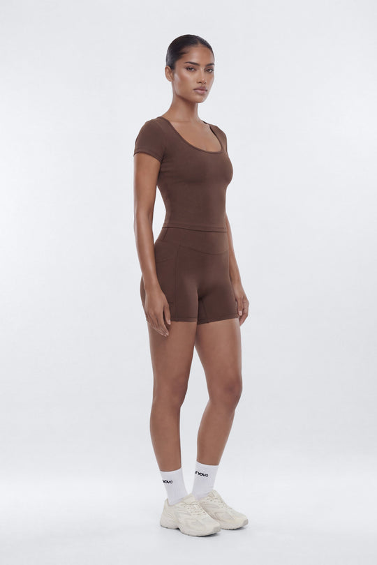 woman wearing a brown shorts an bra in stock and trainer with a white background