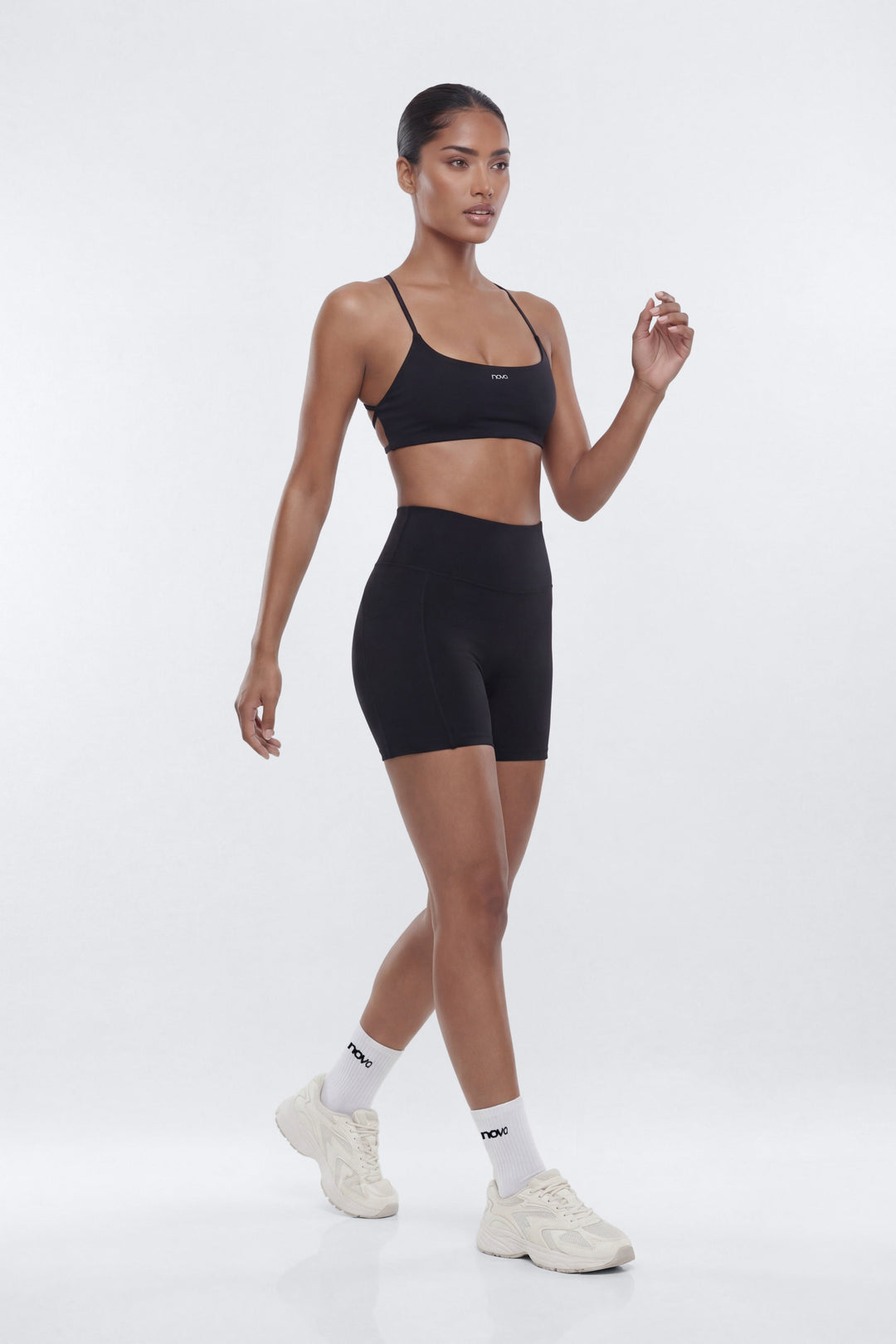 Woman wearing a black sports bra and shorts set on a white background