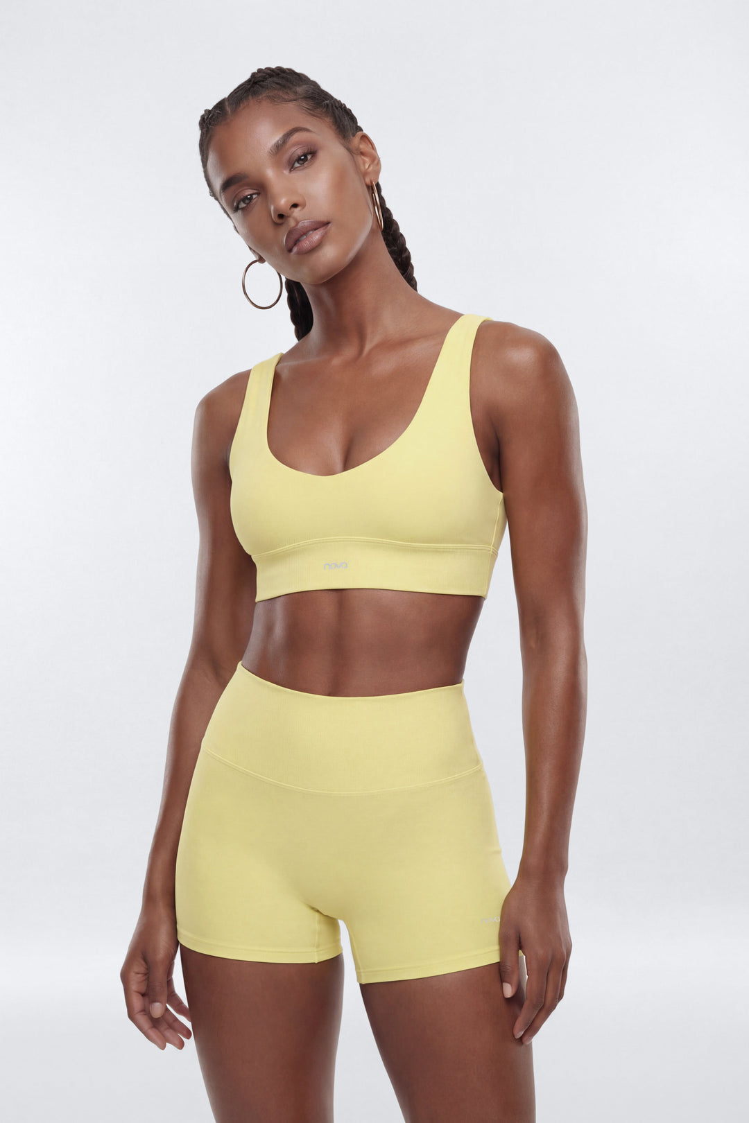 Woman wearing a yellow sports bra and shorts set on a white background