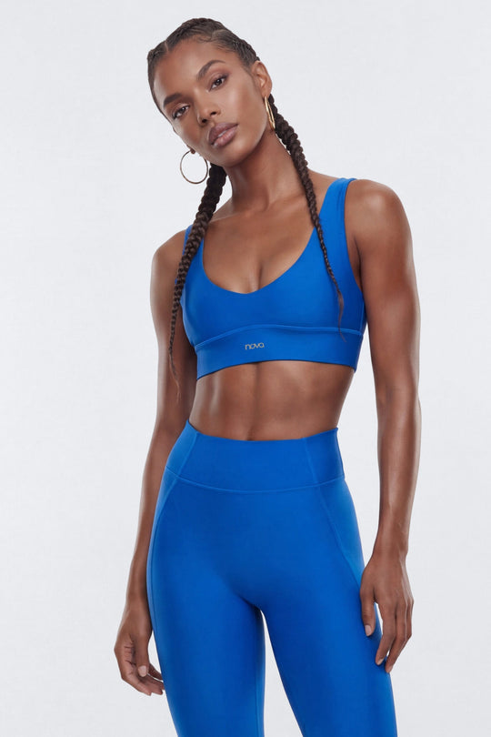 Woman wearing a blue sports bra and leggings on a white background