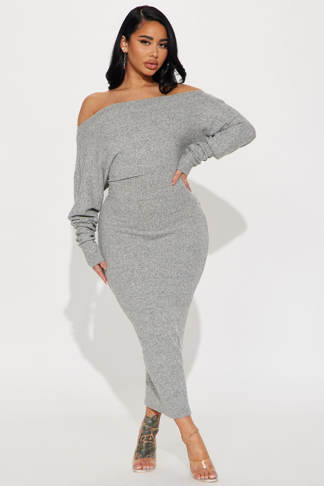 Woman wearing a gray off-shoulder knit dress on a white background