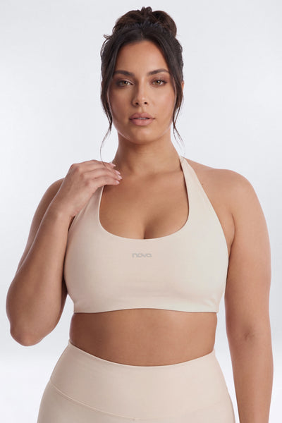 Woman wearing a beige sports bra and leggings on a white background