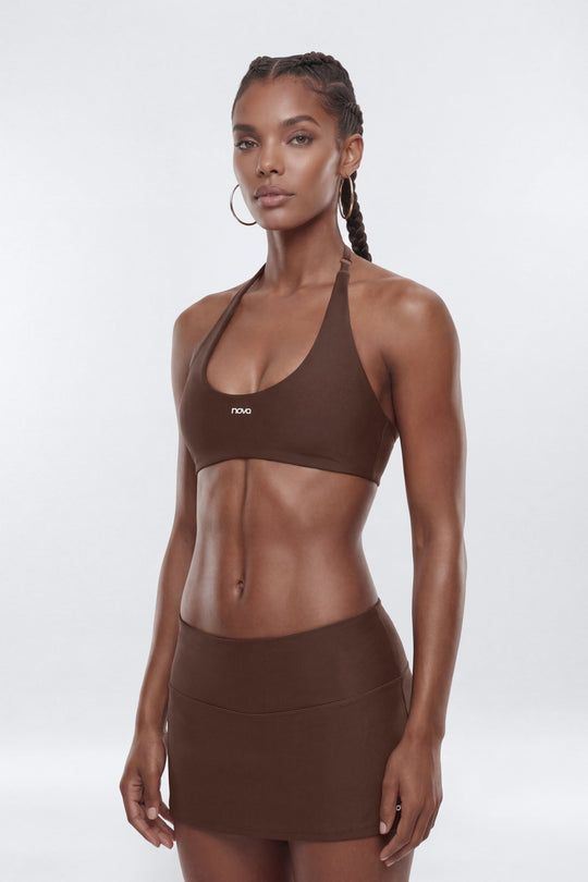Woman wearing a brown sports bra and skirt set on a white background