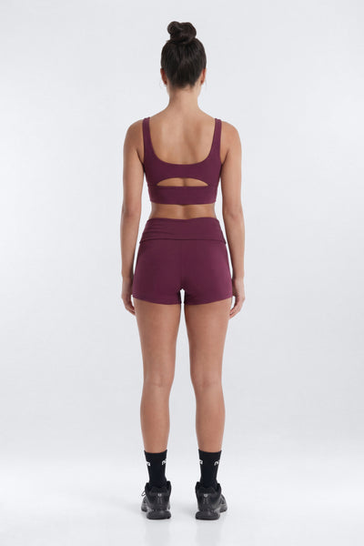 Person wearing a maroon sports bra and shorts set on a white background