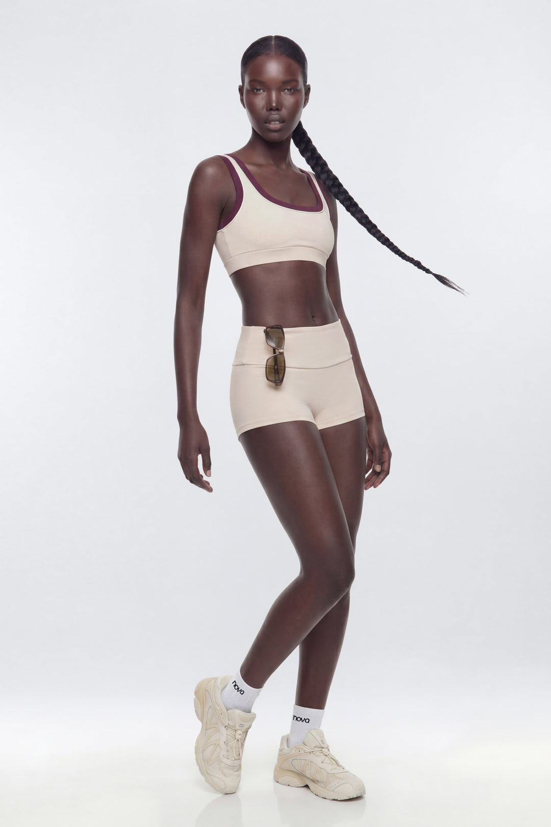 Woman wearing a beige sports bra and shorts set on a white background