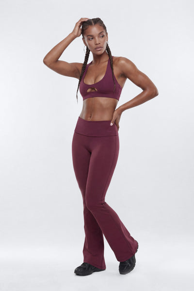 woman modeling a matching burgundy activewear set consisting of a sports bra with a keyhole cutout and high-waisted leggings
