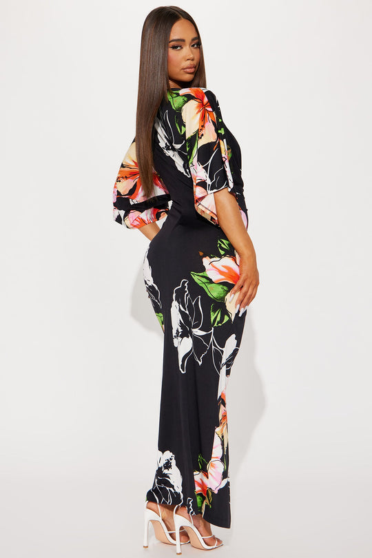 Woman wearing a black dress with colorful floral patterns on a white background