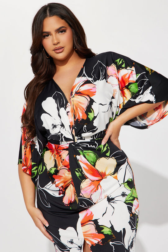 Woman wearing a black floral dress with colorful flowers on a white background