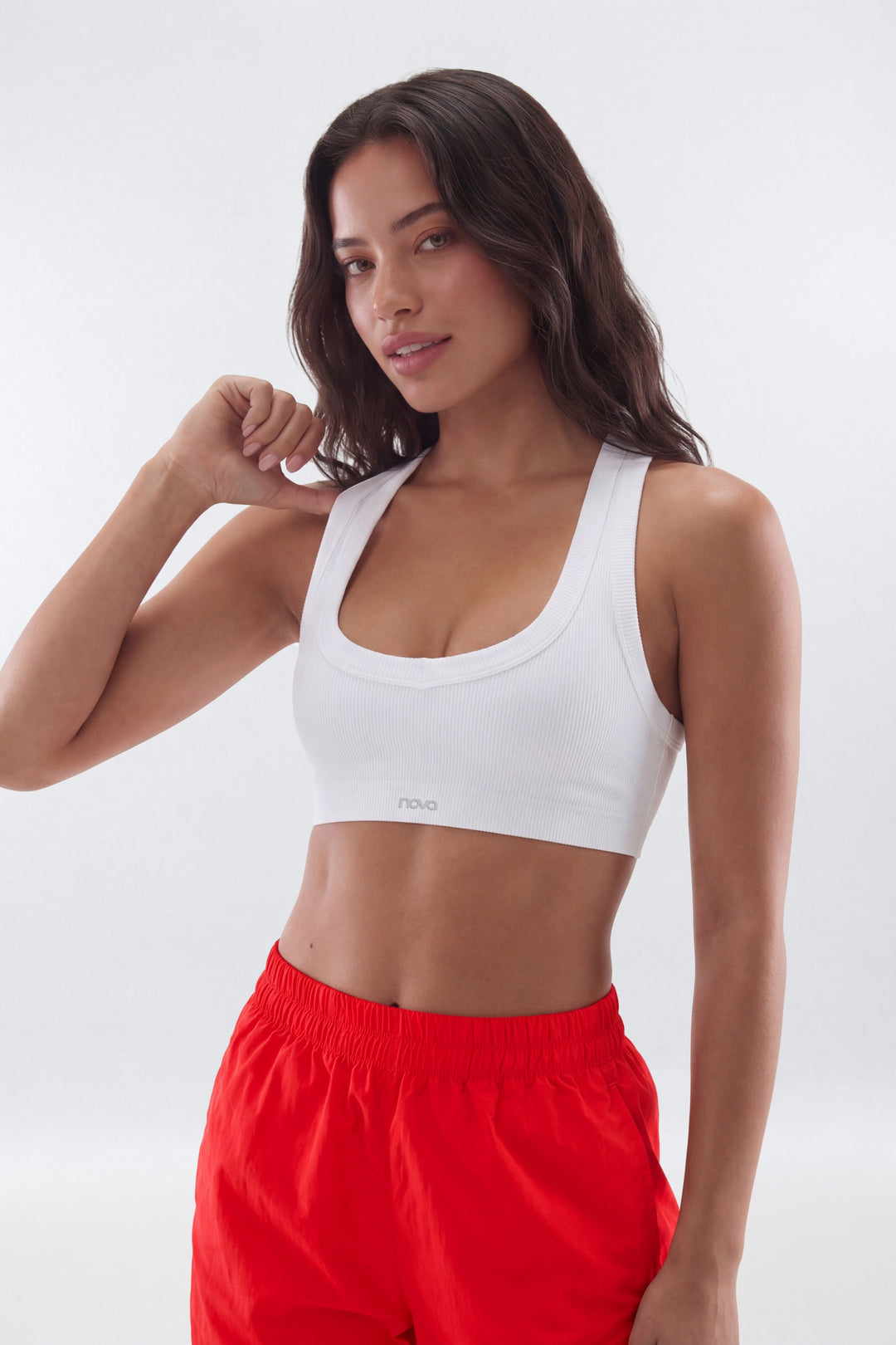 Woman wearing a white sports bra and red shorts on a white background