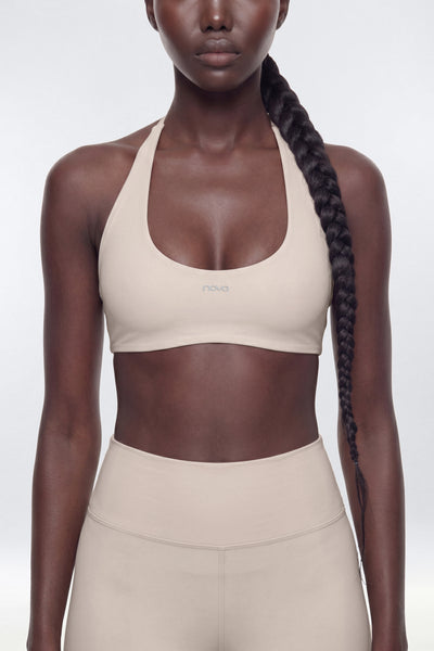 Woman wearing a beige sports bra and leggings on a white background