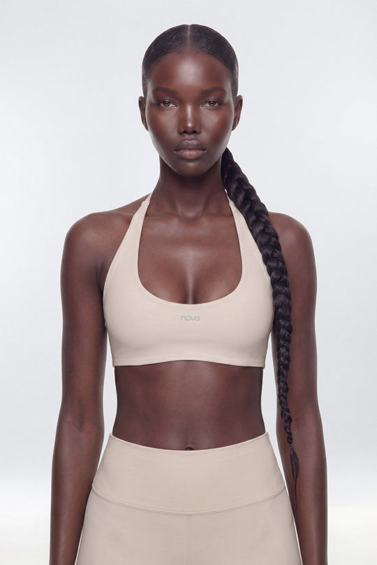 Woman wearing a beige sports bra and leggings on a white background