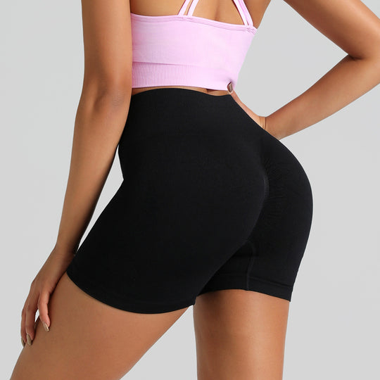 Person wearing a pink sports bra and black shorts on a light gray background