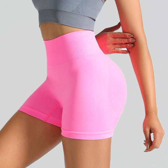 Person wearing bright pink athletic shorts on a gray background