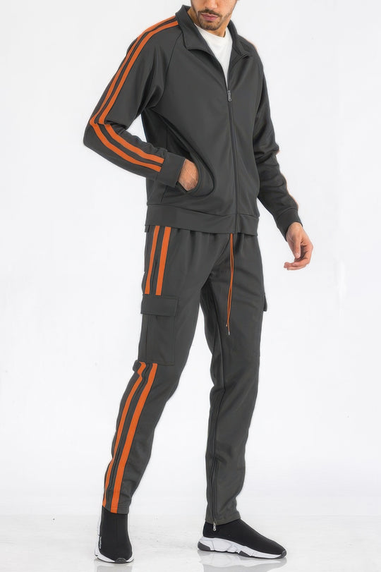 Man wearing a gray tracksuit with orange stripes on a white background