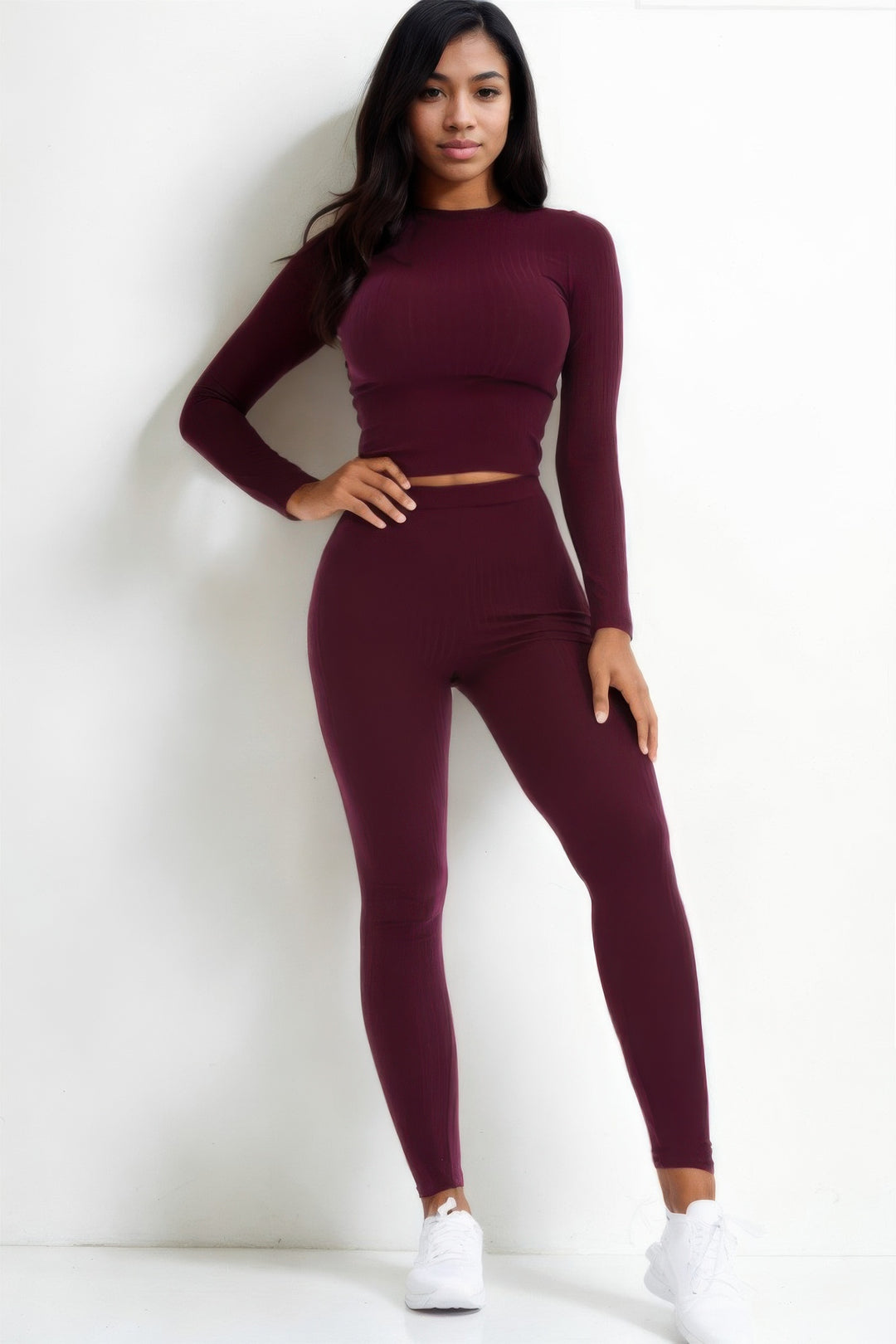 Woman wearing a burgundy two-piece outfit against a white background