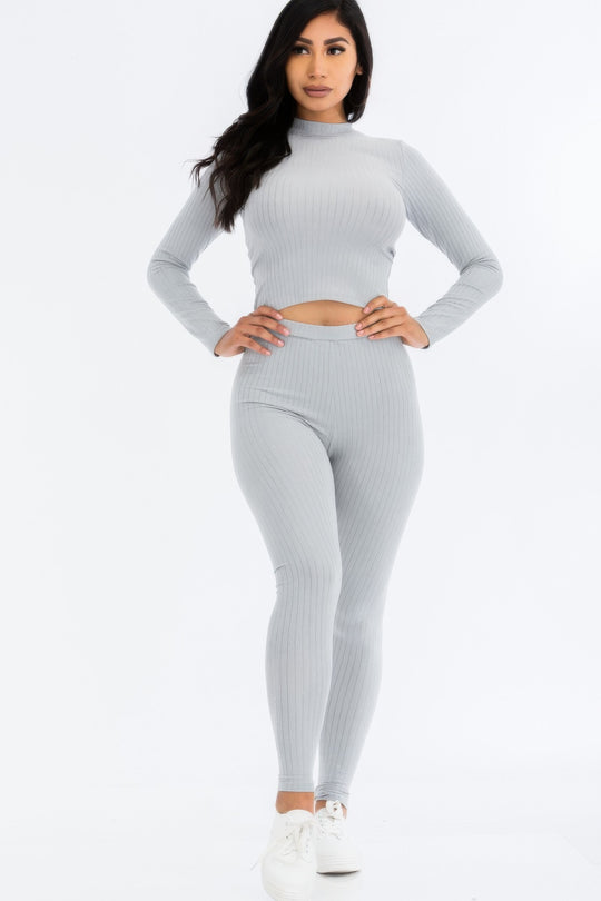 Woman wearing a gray ribbed long-sleeve top and leggings set on a white background