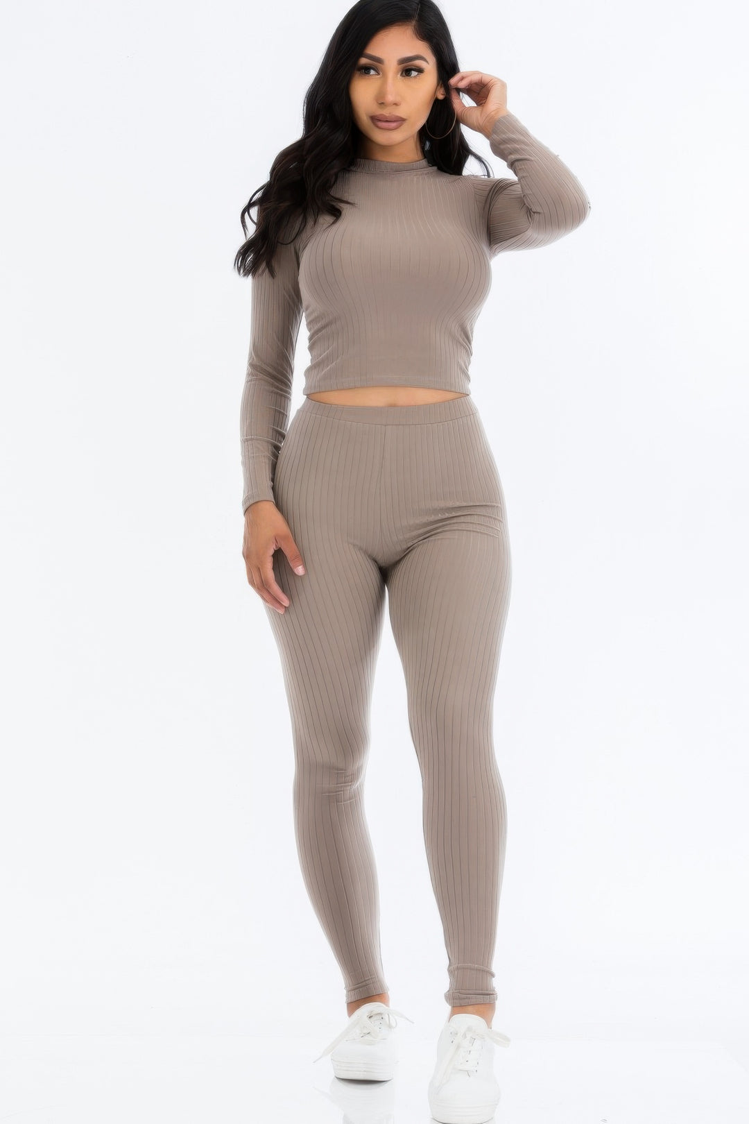 Woman wearing a beige ribbed long-sleeve top and leggings set on a white background