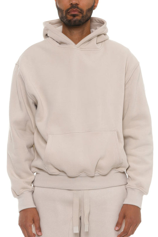 Man wearing a beige hoodie and pants on a white background