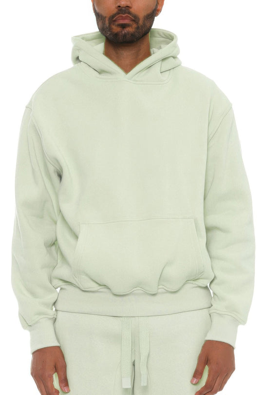 Man wearing a light green hoodie and pants on a white background