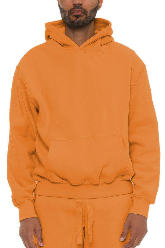 Person wearing an orange hoodie and pants on a white background