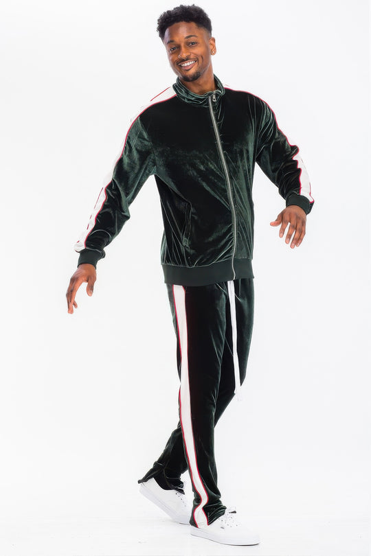 Man wearing a green velvet tracksuit with red stripes on a white background