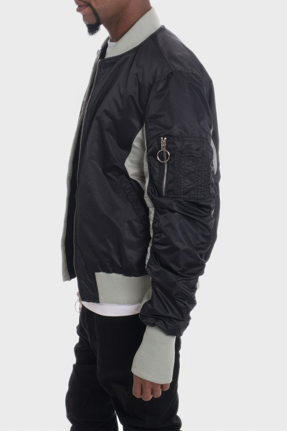 Person wearing a black bomber jacket with white accents on a white background