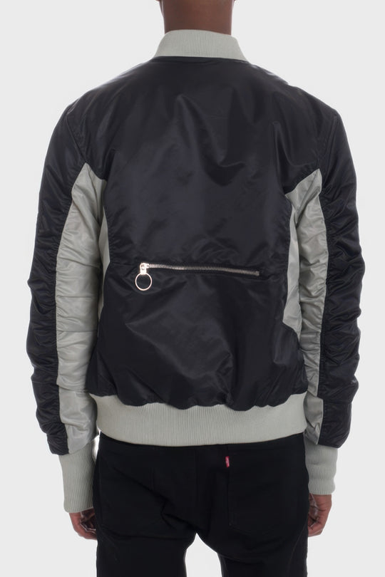 Person wearing a black and gray bomber jacket on a white background