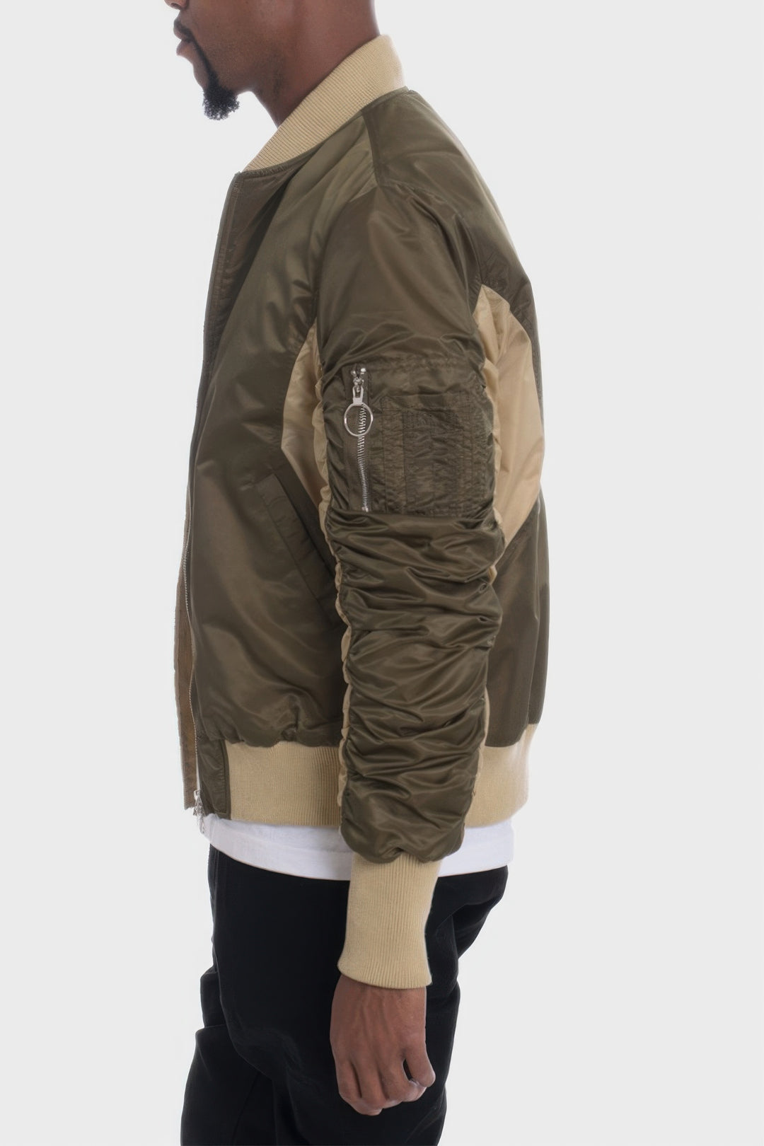 Person wearing a green and beige bomber jacket on a white background