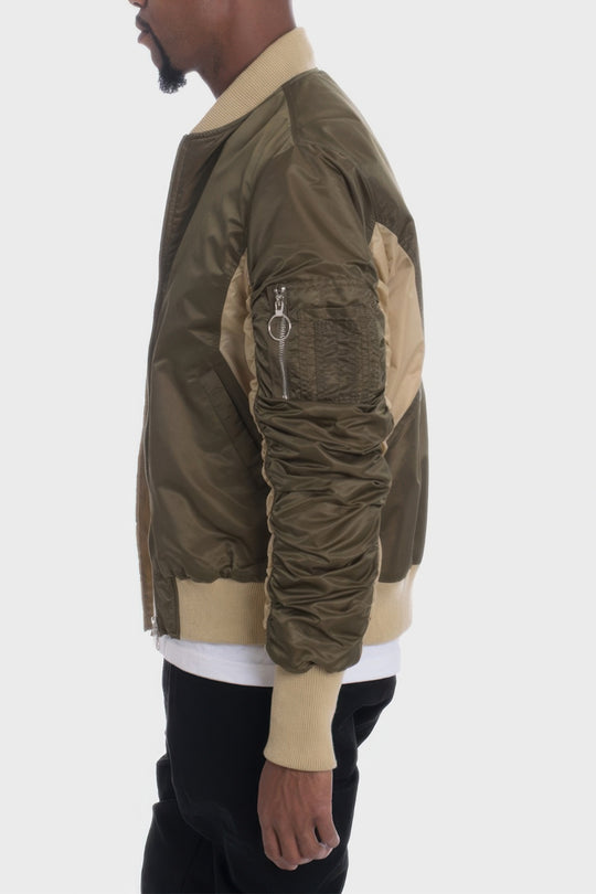 Person wearing a green and beige bomber jacket on a white background