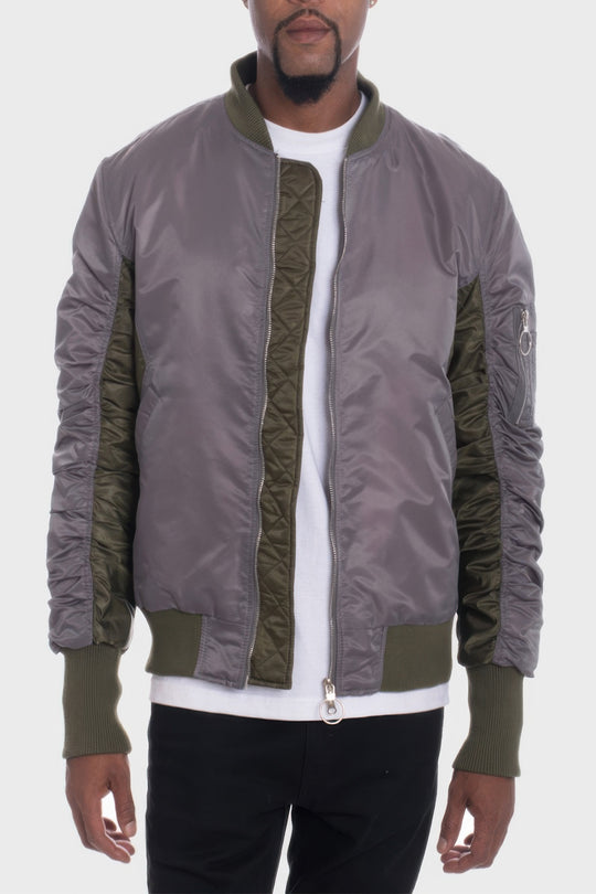 Man wearing a gray and green bomber jacket on a white background