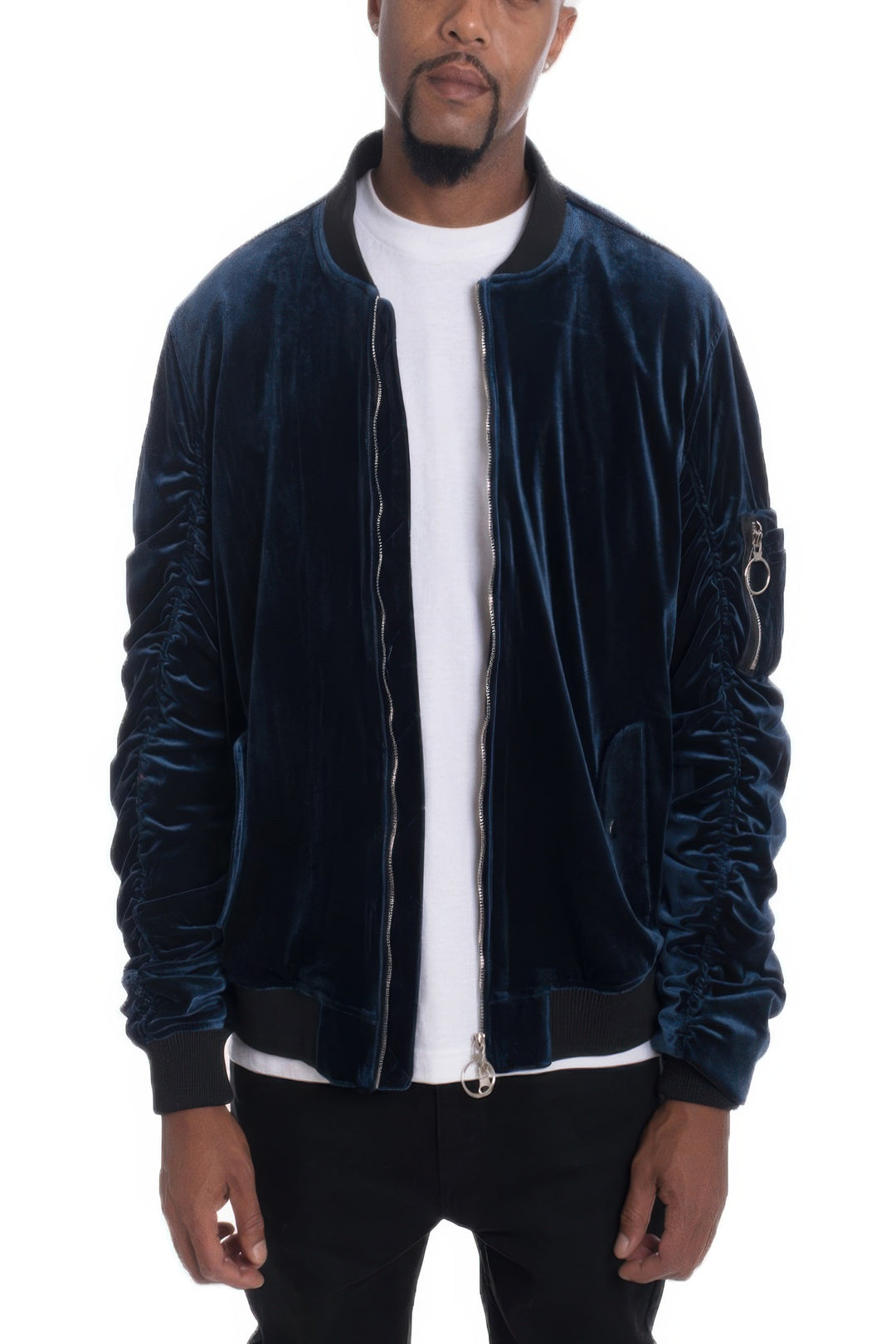 Man wearing a dark blue velvet bomber jacket over a white shirt on a white background