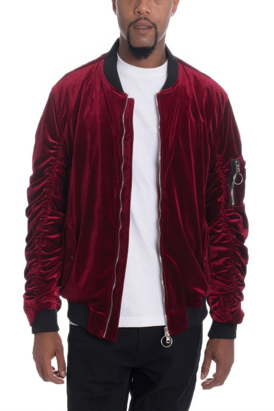 Man wearing a red velvet bomber jacket over a white shirt on a white background