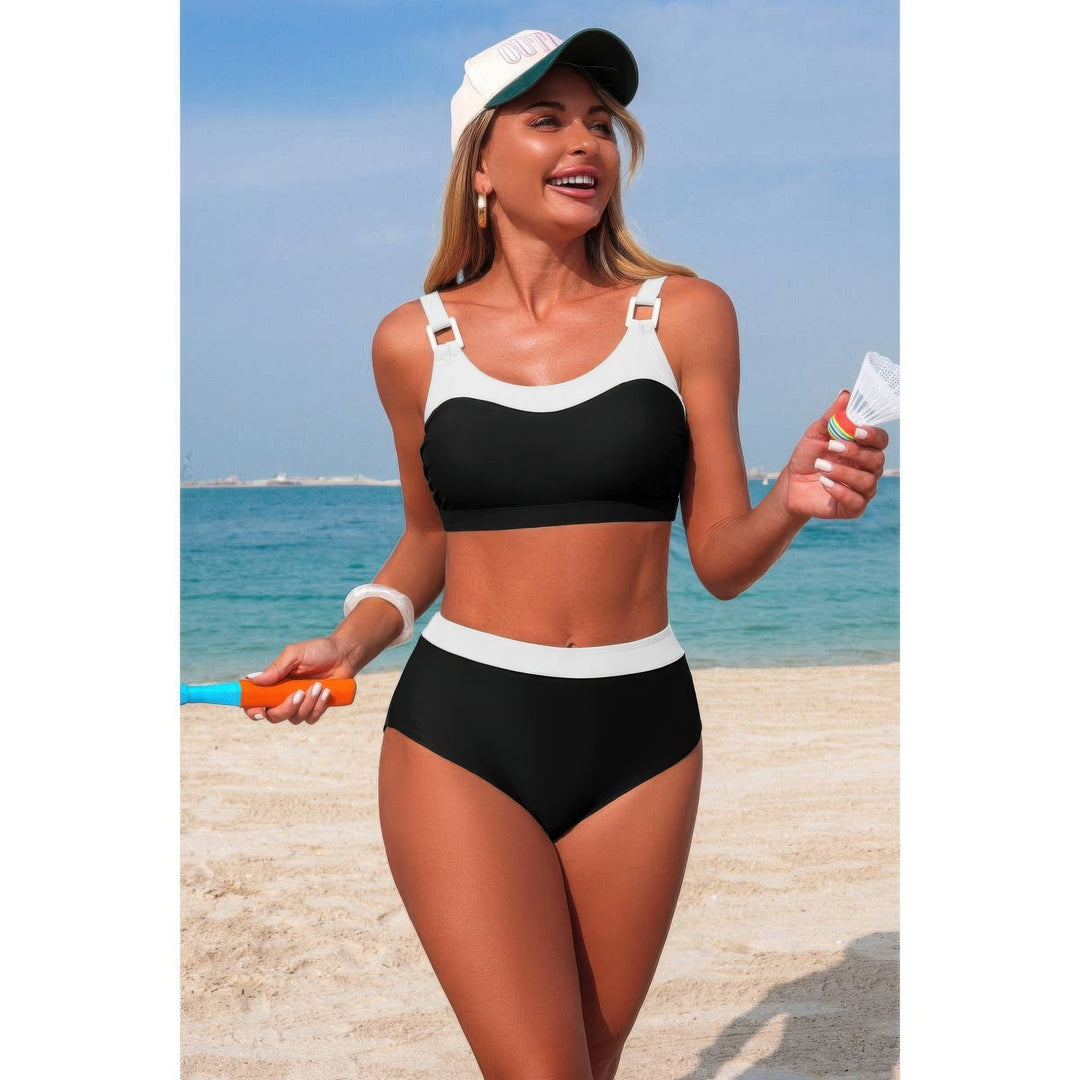 The swimsuit is black with white contrast trim, and she is also wearing a white cap and holding a small bottle and an orange toy.