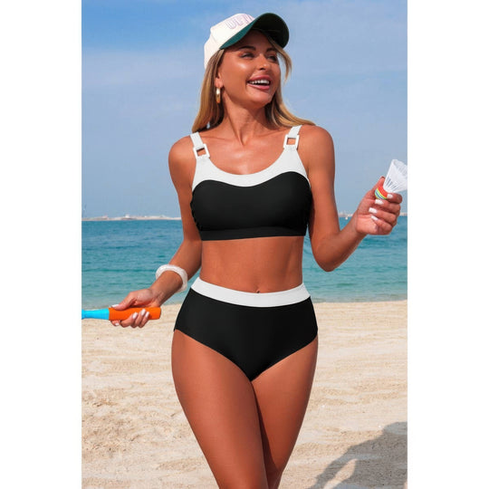 The swimsuit is black with white contrast trim, and she is also wearing a white cap and holding a small bottle and an orange toy.