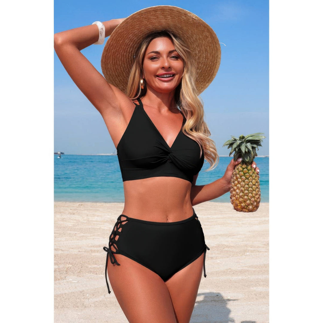 A woman on a beach wearing a black two-piece bikini and a large straw hat, holding a pineapple. The background shows the blue ocean and sky.