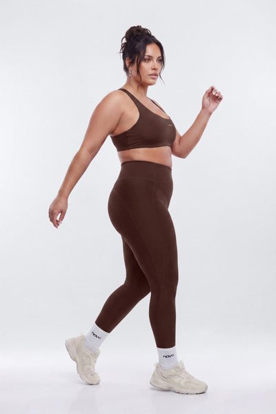 Woman wearing a brown sports bra and leggings set on a white background