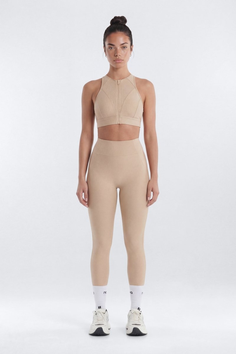 Woman wearing a beige athletic outfit on a white background
