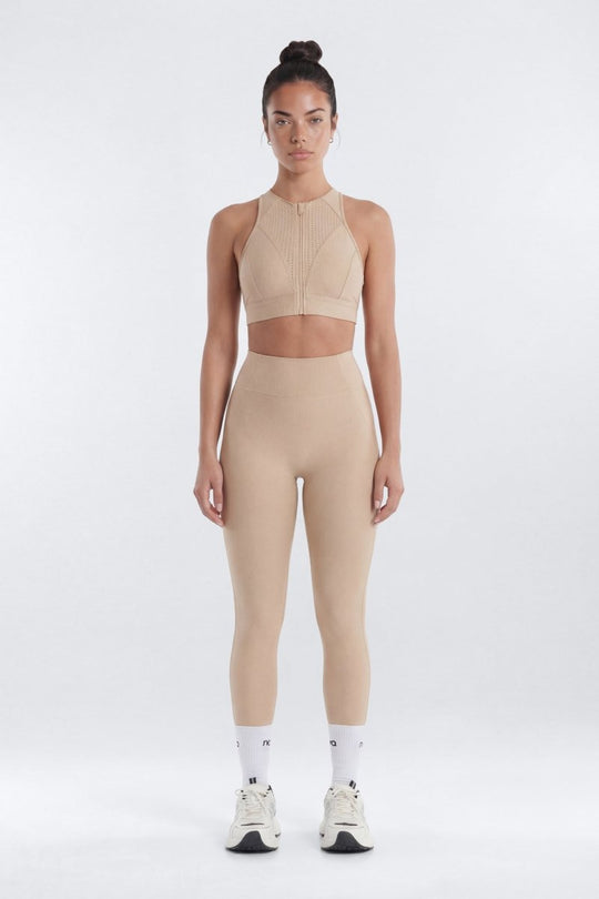 Woman wearing a beige athletic outfit on a white background
