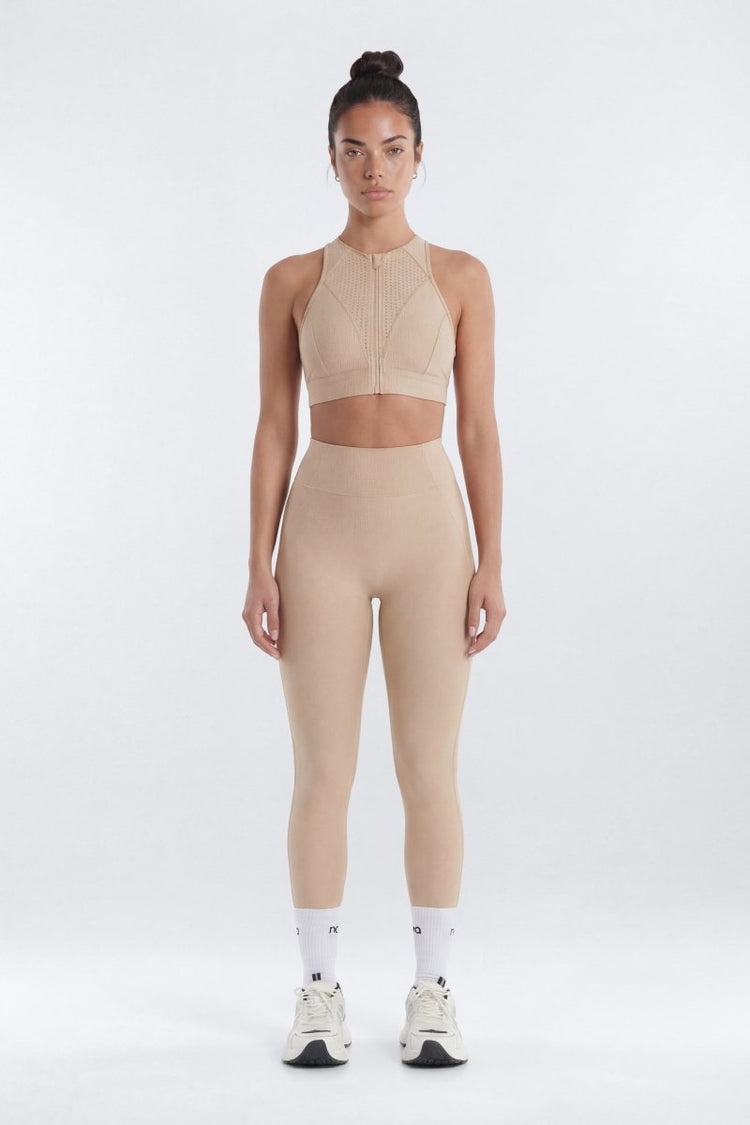 Woman wearing a beige athletic outfit on a white background