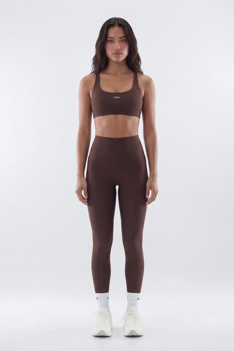 Woman wearing a brown sports bra and leggings set on a white background