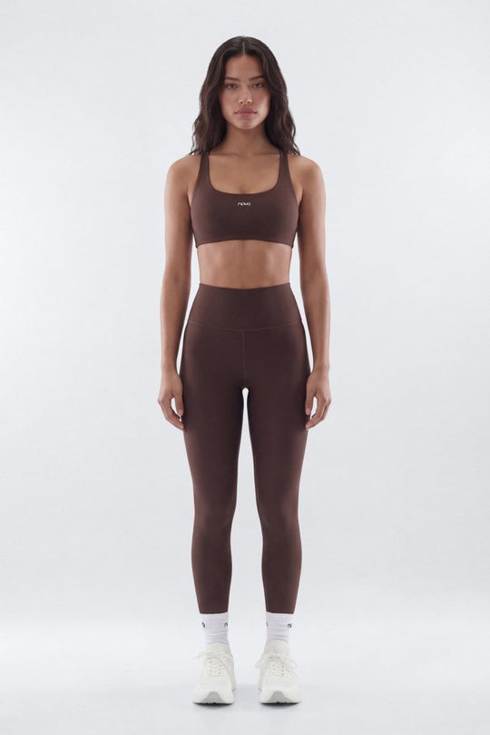 Woman wearing a brown sports bra and leggings set on a white background