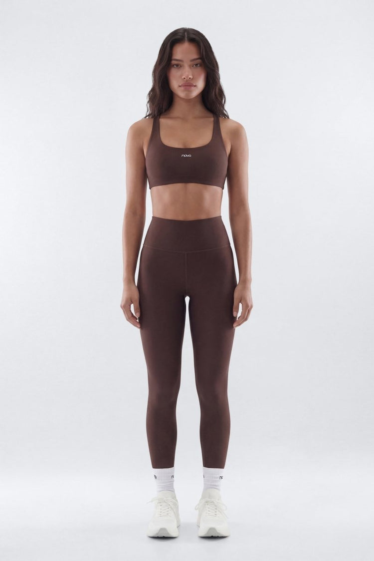 Woman wearing a brown sports bra and leggings set on a white background