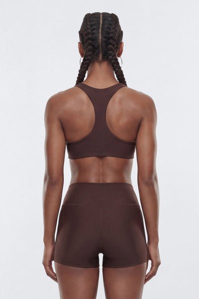 Rear view of a model wearing a matching dark brown activewear set, consisting of a sports bra.